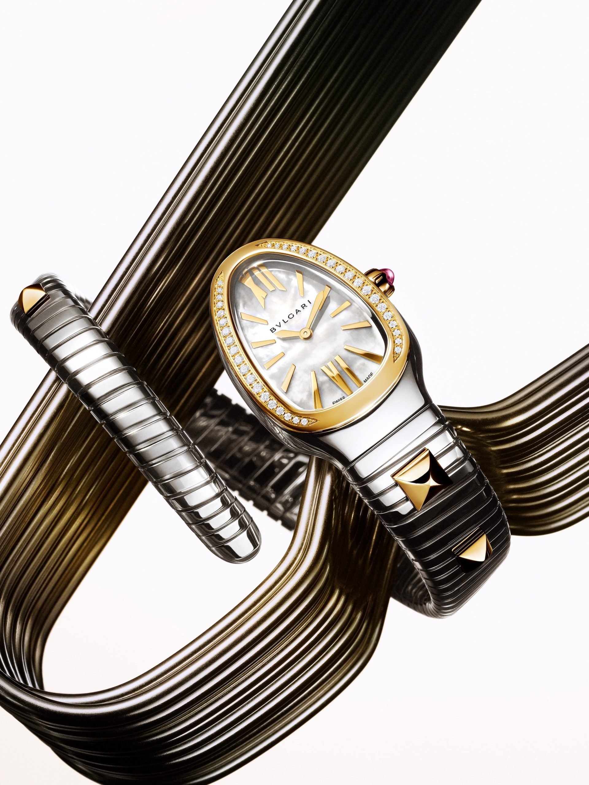 Bvlgari Serpenti Tubogas watch with mother-of-pearl dial and diamond bezel on metallic coil backdrop.