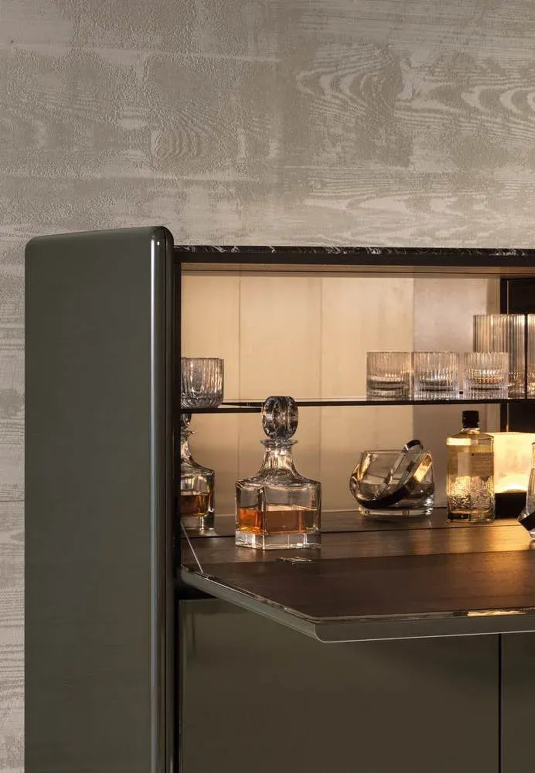 Illuminated luxury home bar cabinet with crystal decanters, ribbed glassware, and whisky bottles.