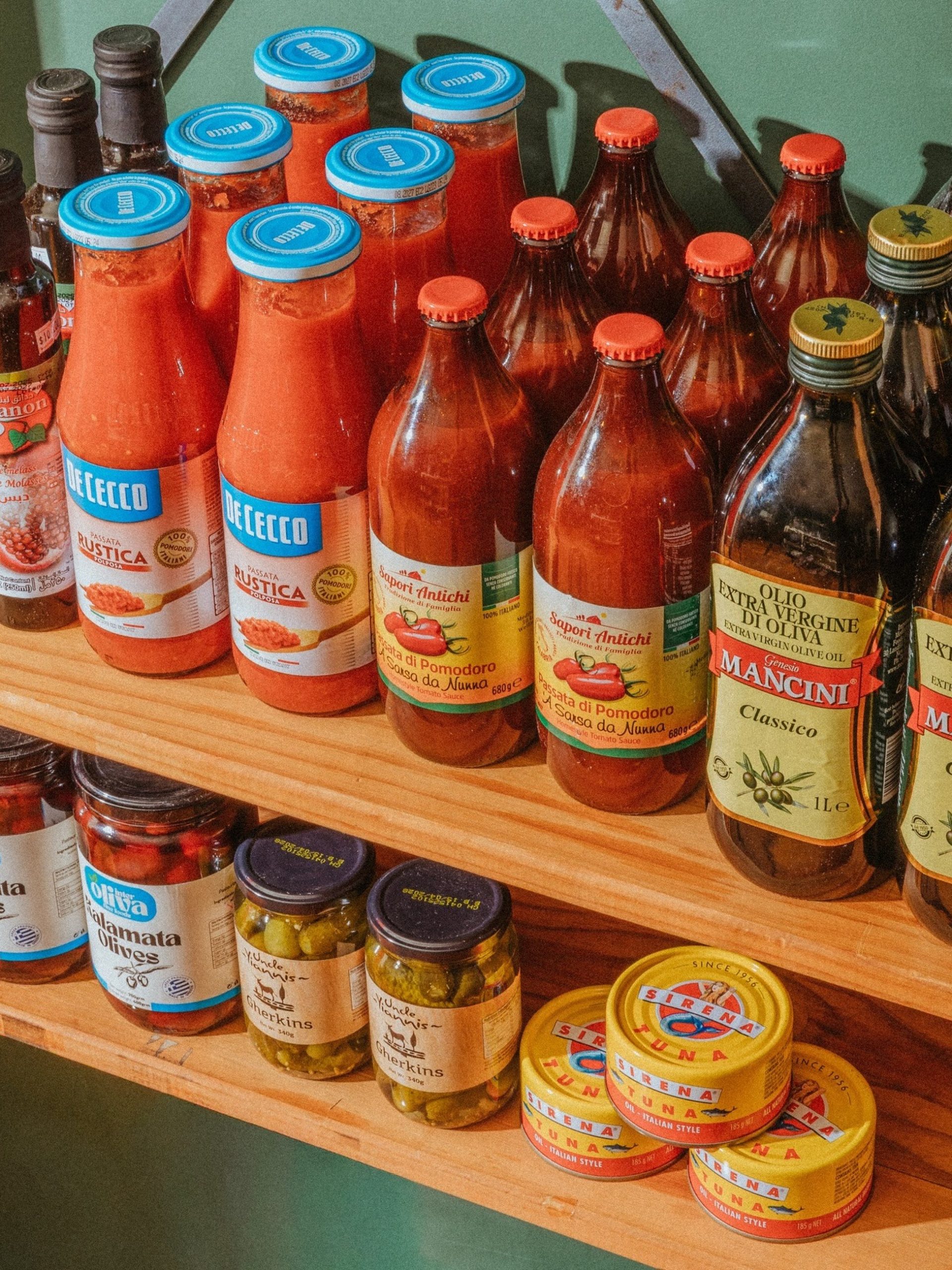 Wooden shelf stocked with Italian tomato sauces, olive oil, olives, gherkins and tuna tins at Wigmore Deli.