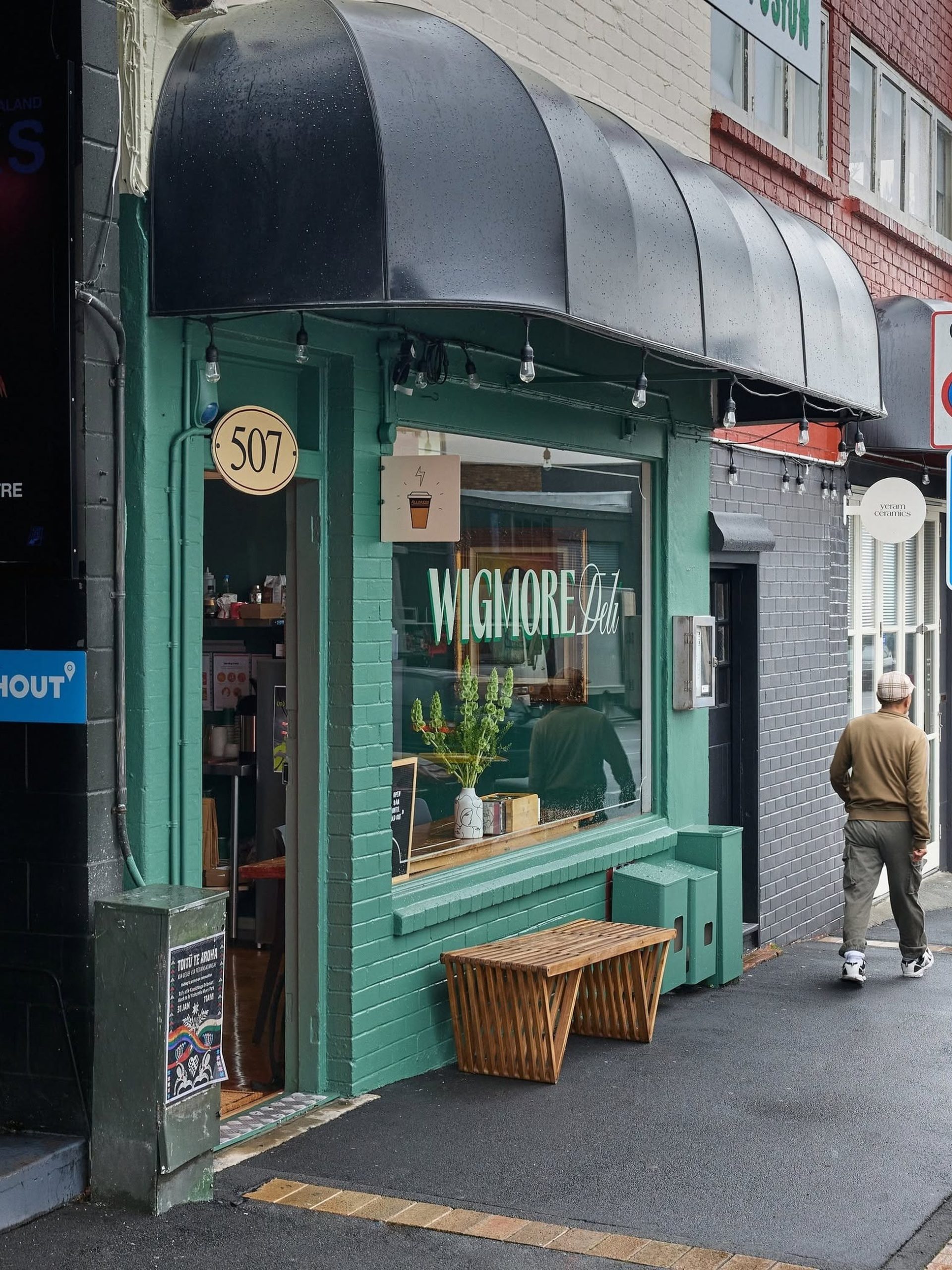 Teal-painted brick facade of Wigmore Deli at number 507 with black barrel awning, Auckland.