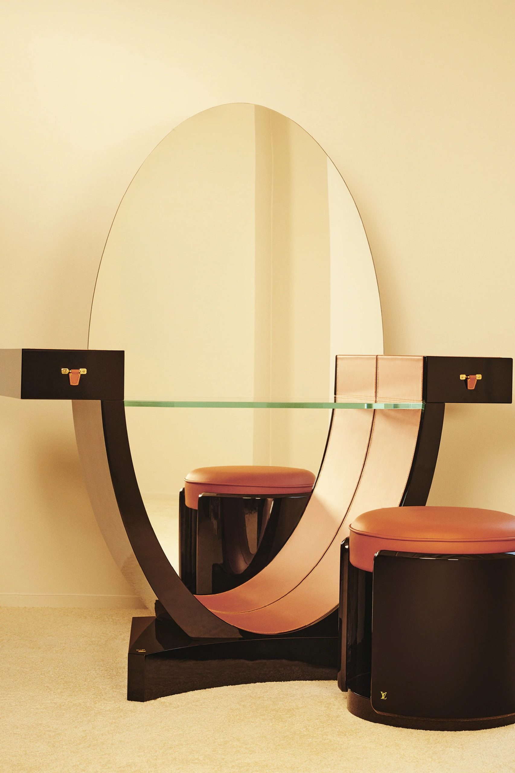 Louis Vuitton Art Deco vanity table with oval mirror, glass top, and cognac leather stools.