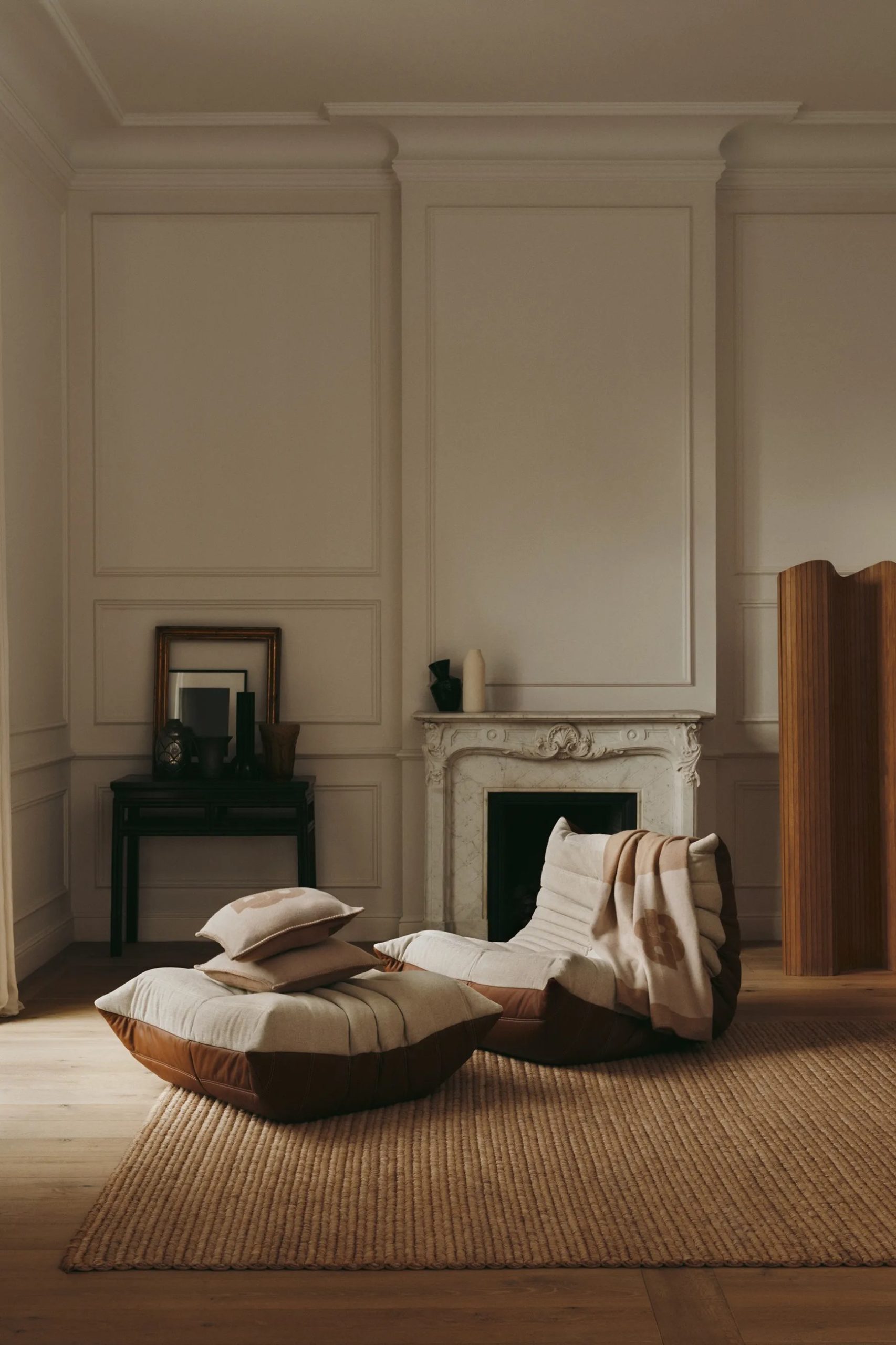 Cream and cognac leather chaise longue before an ornate marble fireplace in a panelled Parisian room.