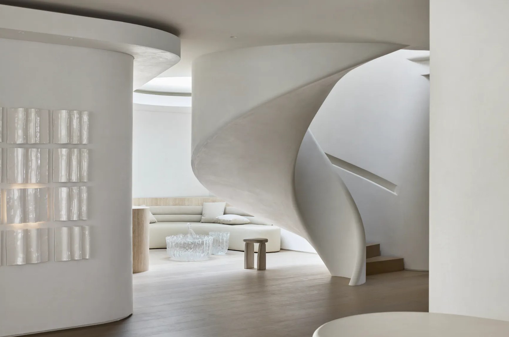 Sculptural white spiral staircase in a minimalist luxury interior with cream furnishings and organic curves.