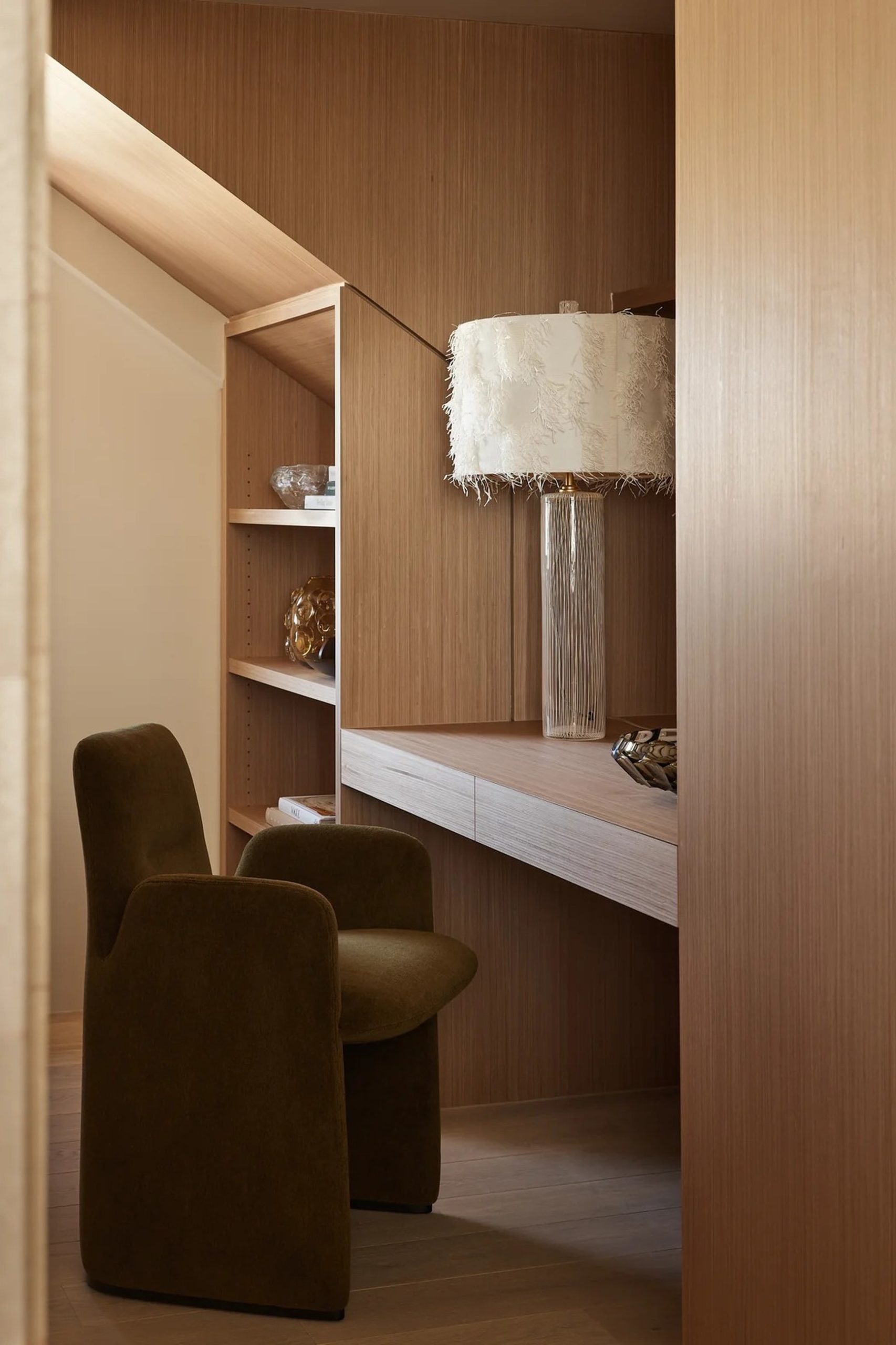 Olive mohair chairs at a built-in oak desk with feather lamp, viewed through timber doorway.