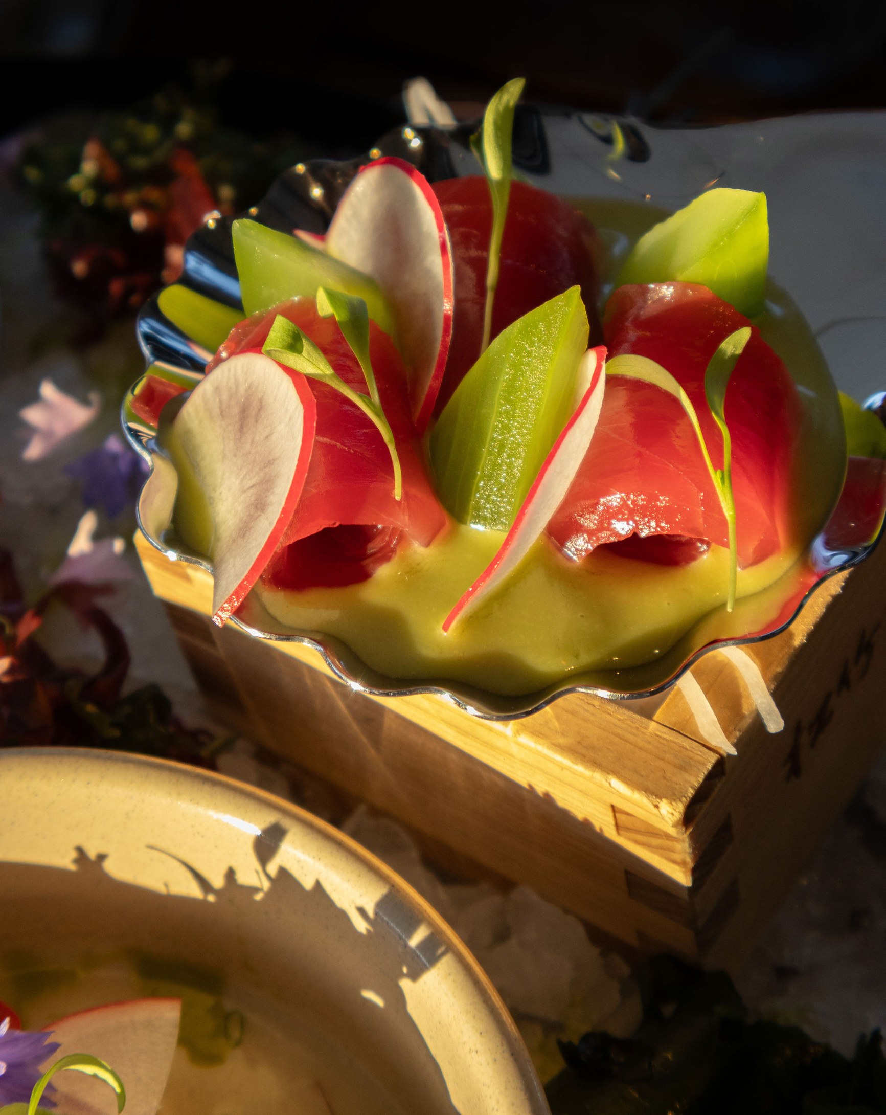 Thinly sliced red and white radishes arranged like a flower in a scalloped glass bowl.