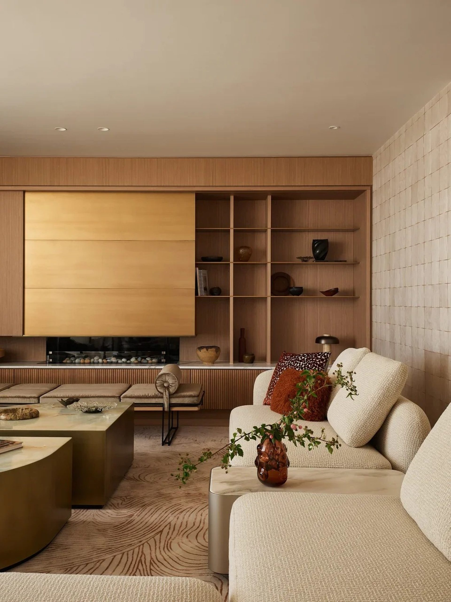 Warm oak and brass living room with cream bouclé sofa, sculptural rug, and curated ceramics.